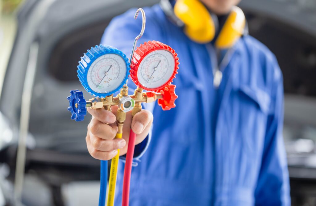 Automotive technician holding refrigerant gauges